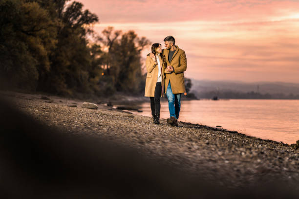 счастливая пара обнимается во время прогулки рядом с берегом реки. - couple autumn embracing bridge стоко�вые фото и изображения