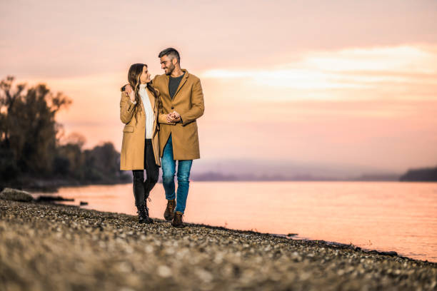 счастливая пара обнимается во время прогулки рядом с берегом реки. - couple autumn embracing bridge стоковые фото и изображения