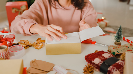 Closeup of woman hands wrapping christmas gift boxes on table at home. New Year and Christmas concept.