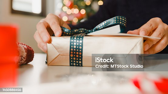 istock Closeup of woman hands writing greeting card with christmas gift boxes on table at home. 1450886456