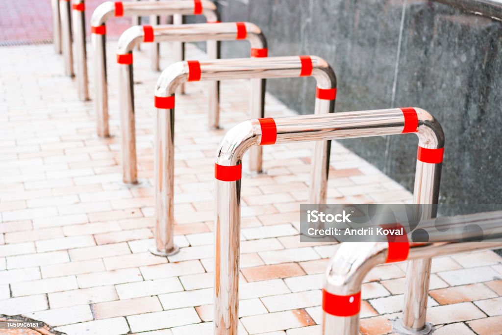 Tubular structure stainless steel bicycle parking with red stripes installed on the street sidewalk. Mirror. Iron. Bike. Sustainable. Ecology. Racks. Free. Empty. Urban Bicycle Stock Photo