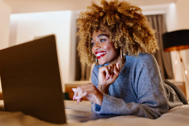 istock Happy woman using laptop at night in the hotel room 1450920721