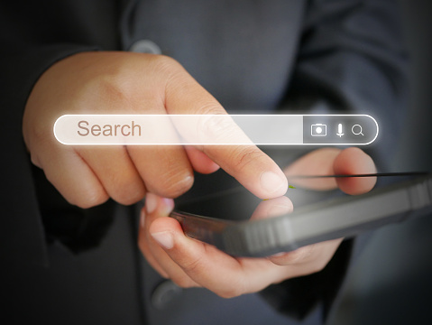 Close-up image of business person's hands using smartphone searching for what they are interested in. Search bar virtual screen, social networks, Search Engine Optimization technology concept
