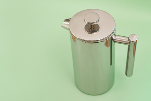 Stainless steel coffee or teapot on a light green background. French-press. Coffee. Coffeemaker. Coffeepot. Espresso. Kitchenware. Pot. Preparation. Stainless. Steel. Tea. Accessories. Brewed. Cap