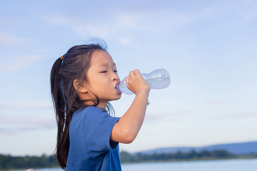 Asian child girl drinking water after playing outdoor