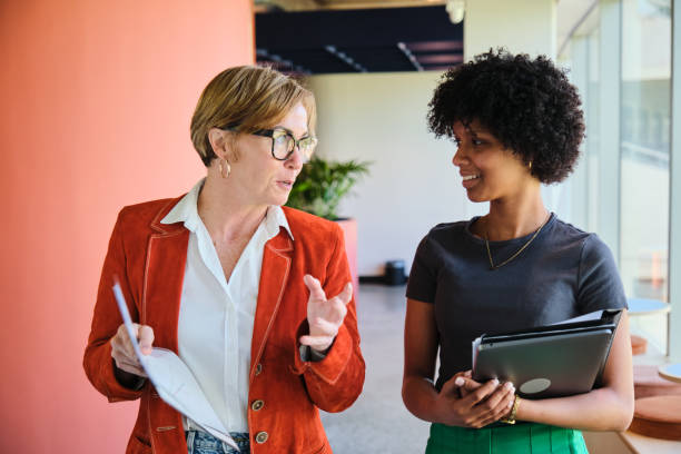istock Smiling businesswomen talking while walking together in an office 1450931313