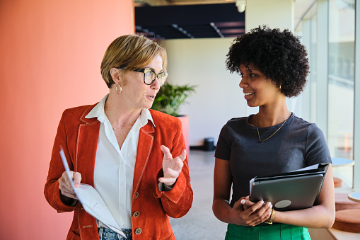 Smiling businesswomen talking while walking together in an office