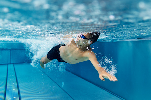 Teenage boy swimming crawl in pool