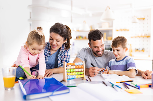 Happy parents assisting their kids in home schooling.