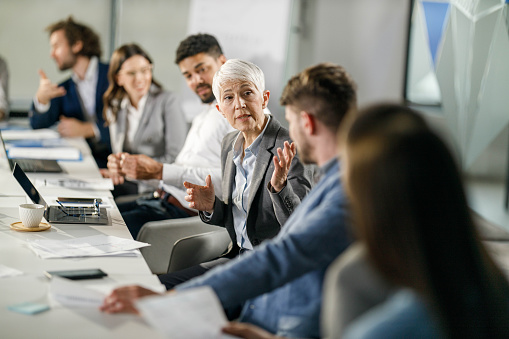 Mature businesswoman communicating with her colleagues on a meeting in the office.