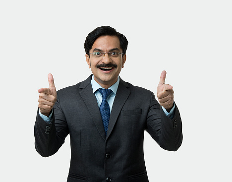Portrait of confident businessman gesturing thumbs up on white background