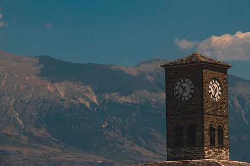 A outdoor view of a clocktower against blue sky and mountain landscape