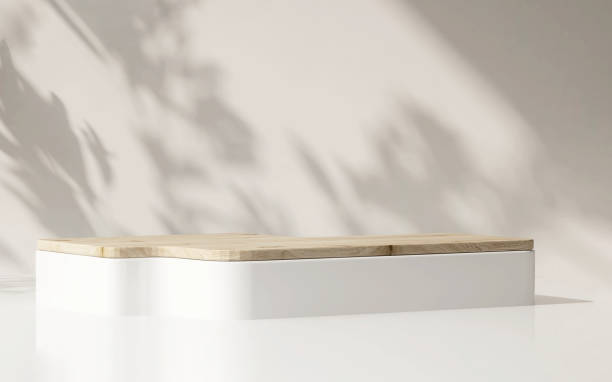 istock Modern, minimal square white podium with wooden top on white counter table in dappled sunlight and shadow on cream white wall 1450953994