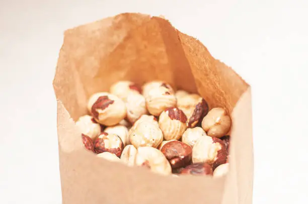 The daily rate of hazelnuts for an adult is packed in a brown paper bag on a white table. View from above.