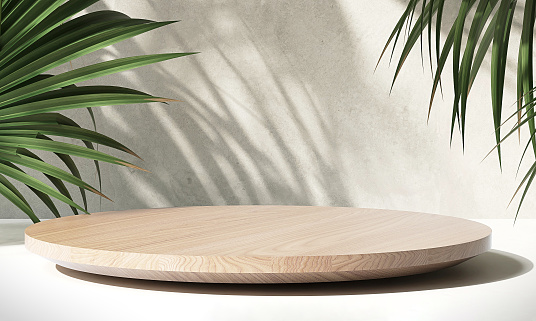 Minimal modern wooden round tray podium on white glossy table counter, green tropical palm in sunlight, leaf shadow on concrete wall background for luxury beauty, organic, health, cosmetic, jewelry fashion product display backdrop