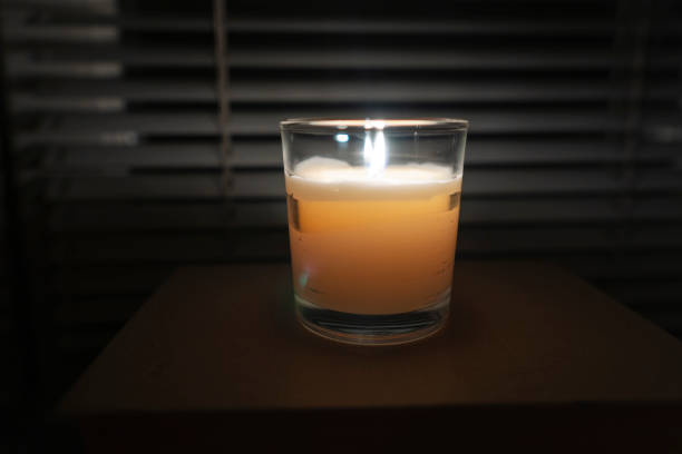 istock A candle with a glass cup stands in a dark empty room by the window 1450956653