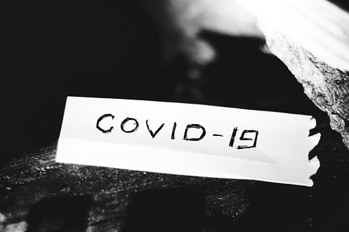 Historic vanquished COVID-19 virus written on a piece of paper. Black and white photography.