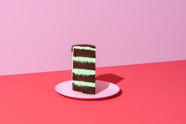 Slice of cake minimalist on a red background. Chocolate and mint layered cake. Single slice of cake minimalist on a vibrant-colored table. Homemade layered cake with mint-flavored buttercream and chocolate sponge base. birthday cake green stock pictures, royalty-free photos & images
