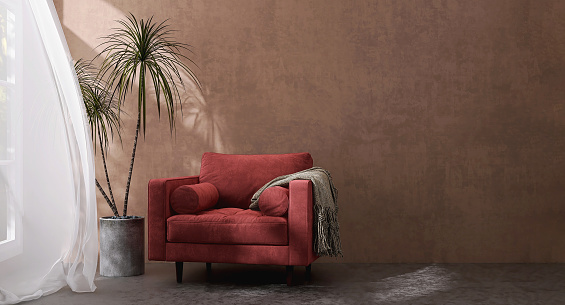Luxury design of velvet red armchair sofa with blanket, dracaena plants, in sunlight from window with blowing white sheer curtain on tuscan brown venetian plaster wall and dark cement floor for interior design decoration background