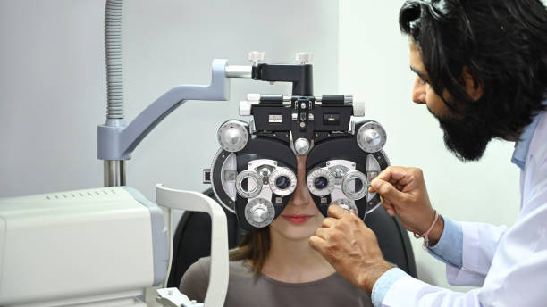 istock Young female patient checking eye vision with phoropter eyesight measurement testing machine in clinic. 1450965054