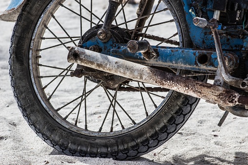Holbox, Mexico – December 29, 2017: Wheel of a rusty motorcycle at the beach in mexico