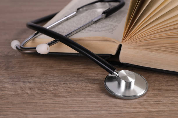 istock Open student textbook and stethoscope on wooden table, closeup. Medical education 1450966927