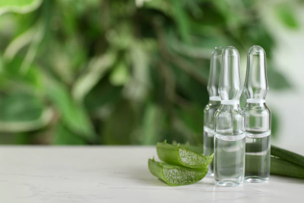 istock Pharmaceutical ampoules with medication and aloe leaves on white table, closeup. Space for text 1450967220