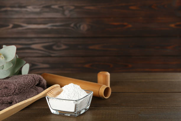 istock Tooth powder, towel, brush and eucalyptus on wooden table, space for text 1450968348