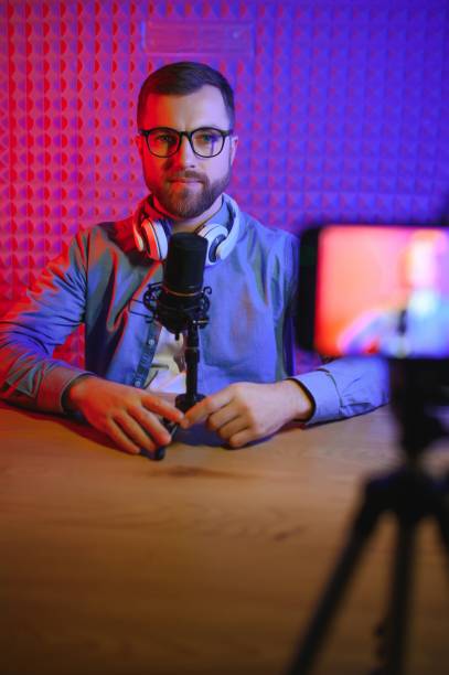 istock Young man recording or streaming podcast using microphone at his small broadcast studio. Content creator. 1450969306