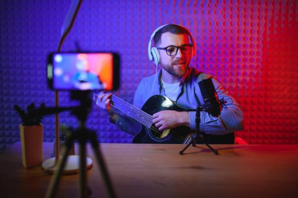 istock vlogger using smartphone to film podcast in studio. blogger with mobile phone, microphone and headphones filming video for social media broadcasting career. 1450969357