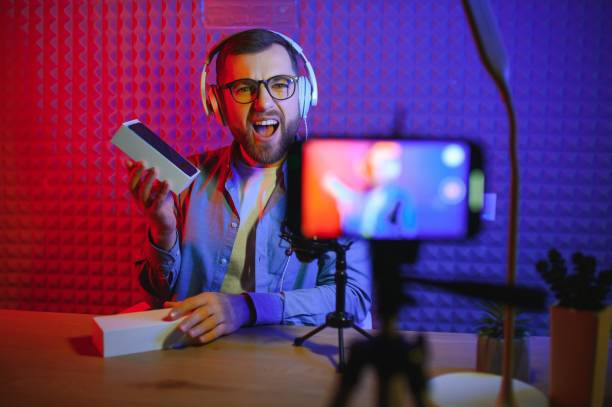 istock vlogger using smartphone to film podcast in studio. blogger with mobile phone, microphone and headphones filming video for social media broadcasting career. 1450969706
