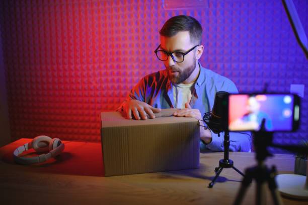 istock vlogger using smartphone to film podcast in studio. blogger with mobile phone, microphone and headphones filming video for social media broadcasting career. 1450970291
