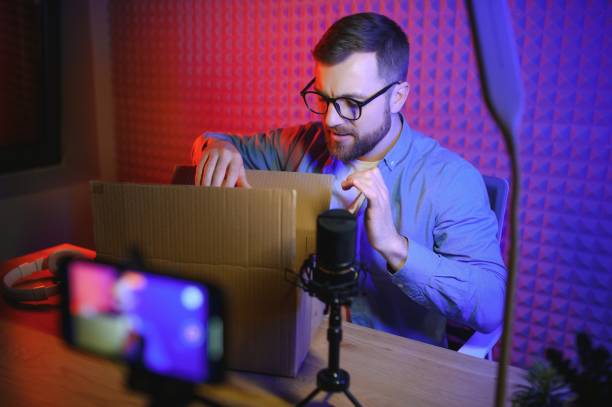 istock Handsome young man gesturing while unpacking parcel, excited, clenches fists in triumph. Joyful male vlogger. Concept of people and social networks. 1450970461
