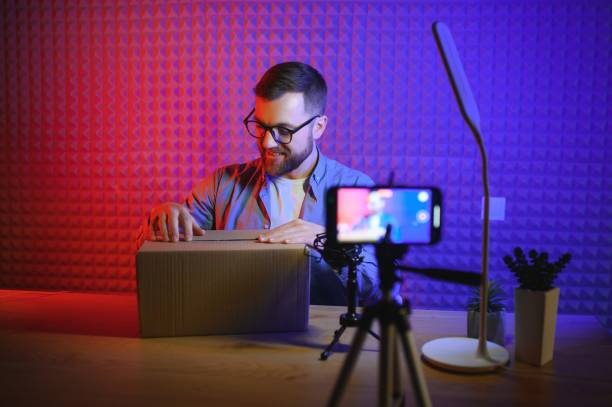 istock Handsome young man gesturing while unpacking parcel, excited, clenches fists in triumph. Joyful male vlogger. Concept of people and social networks. 1450970463