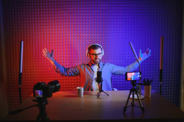 istock vlogger using smartphone to film podcast in studio. blogger with mobile phone, microphone and headphones filming video for social media broadcasting career. 1450970800