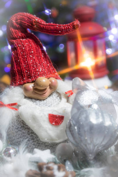 istock Christmas gnome with a glowing Christmas tree in the background and falling snow 1450970812