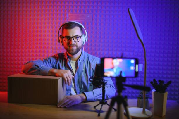 istock Young man recording or streaming podcast using microphone at his small broadcast studio. Content creator. 1450971157