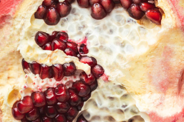 Half of fresh pomegranate fruit as a textured background. Ripe pomegranate cracked in a half with red juicy seeds exposed