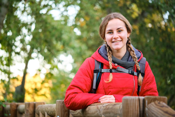 Happy young female hiker posing looking at you in the forest.