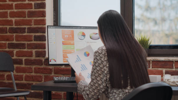 istock Asian woman analyzing papers to plan business project 1450974549