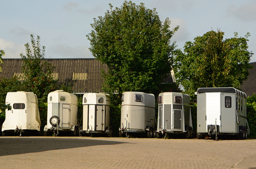 Summer day: Medium group of empty horse trailers standing side by side.