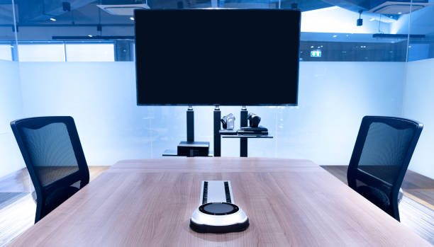 istock Wireless microphone portable on middle meeting table with blank screen television in Video conference meeting room 1450976376