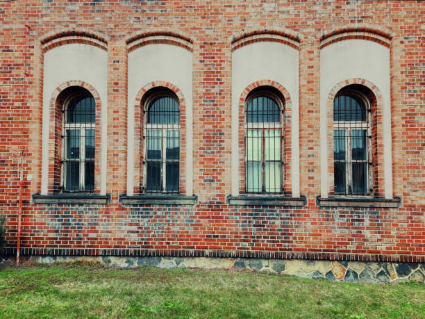istock Brick wall with four arched barred windows - outside view 1450976771