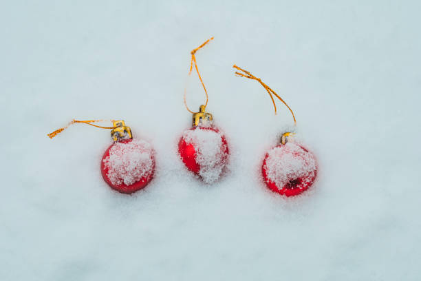 Christmas baubles covered with snow, three red baubles