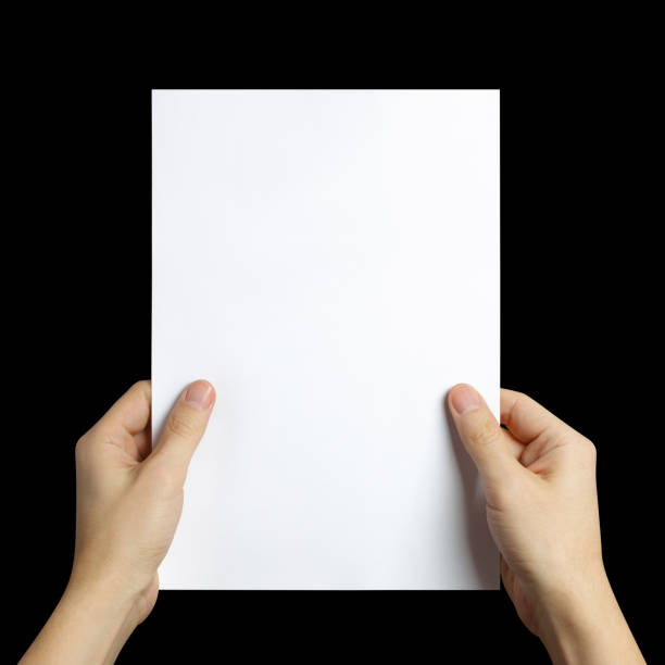 istock Hands holding a sheet of white paper on black 1450986520