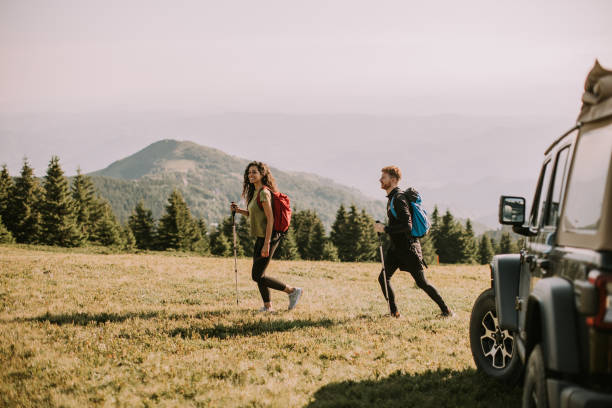 istock Smiling couple walking with backpacks over green hills 1450991357