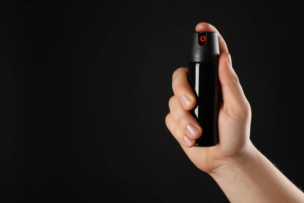 istock Man holding pepper spray on black background, closeup. Space for text 1450994841