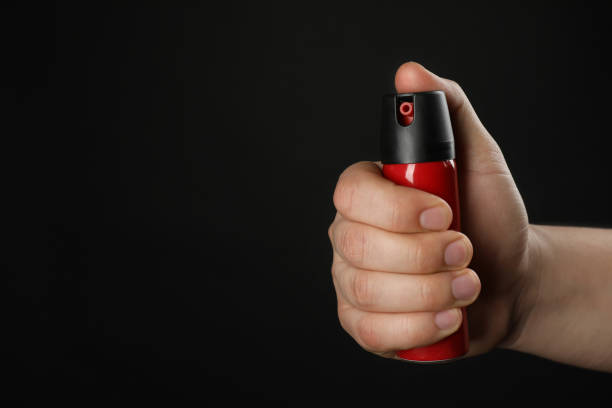 istock Man holding pepper spray on black background, closeup. Space for text 1450995646
