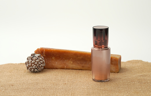 cosmetic spa oil container on blur pine cone and amber background