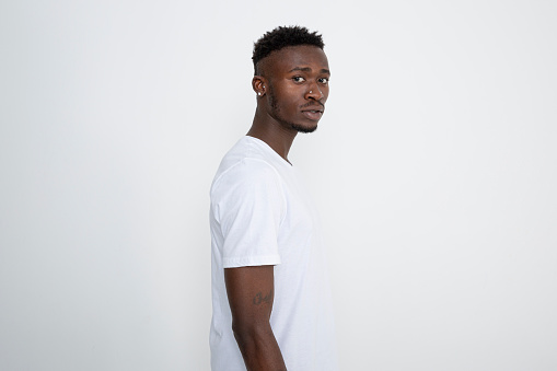African-American man in white t-shirt against white background. Looking at camera.
